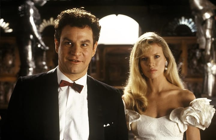 man in a cheap tuxedo and a woman in a white dress standing in a room full of suits of armor