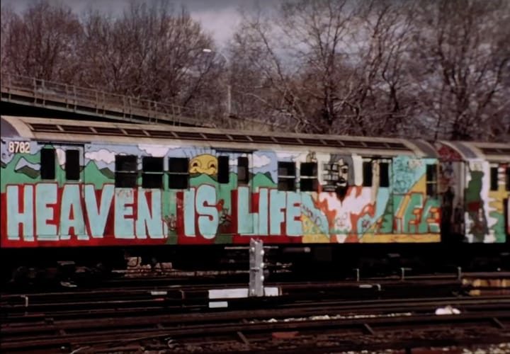 Still from film Stations of the Elevated with subway car graffitied with the words Heaven Is Life